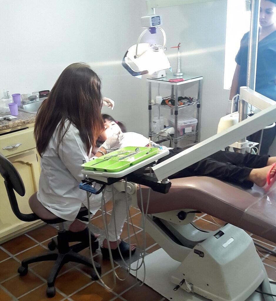 Dentista atendiendo a una niña en consulta odontológica infantil