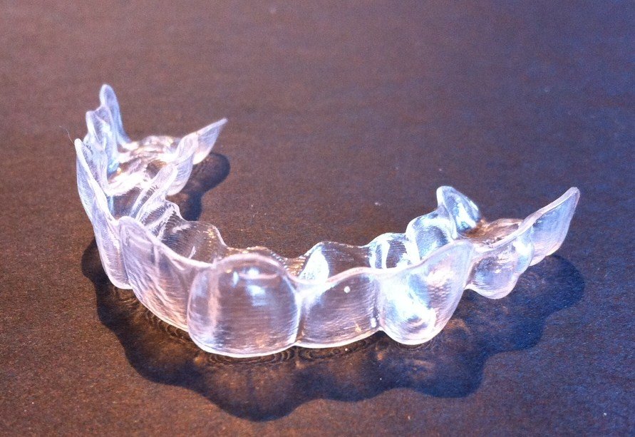 Alineador transparente de ortodoncia invisible sobre superficie oscura